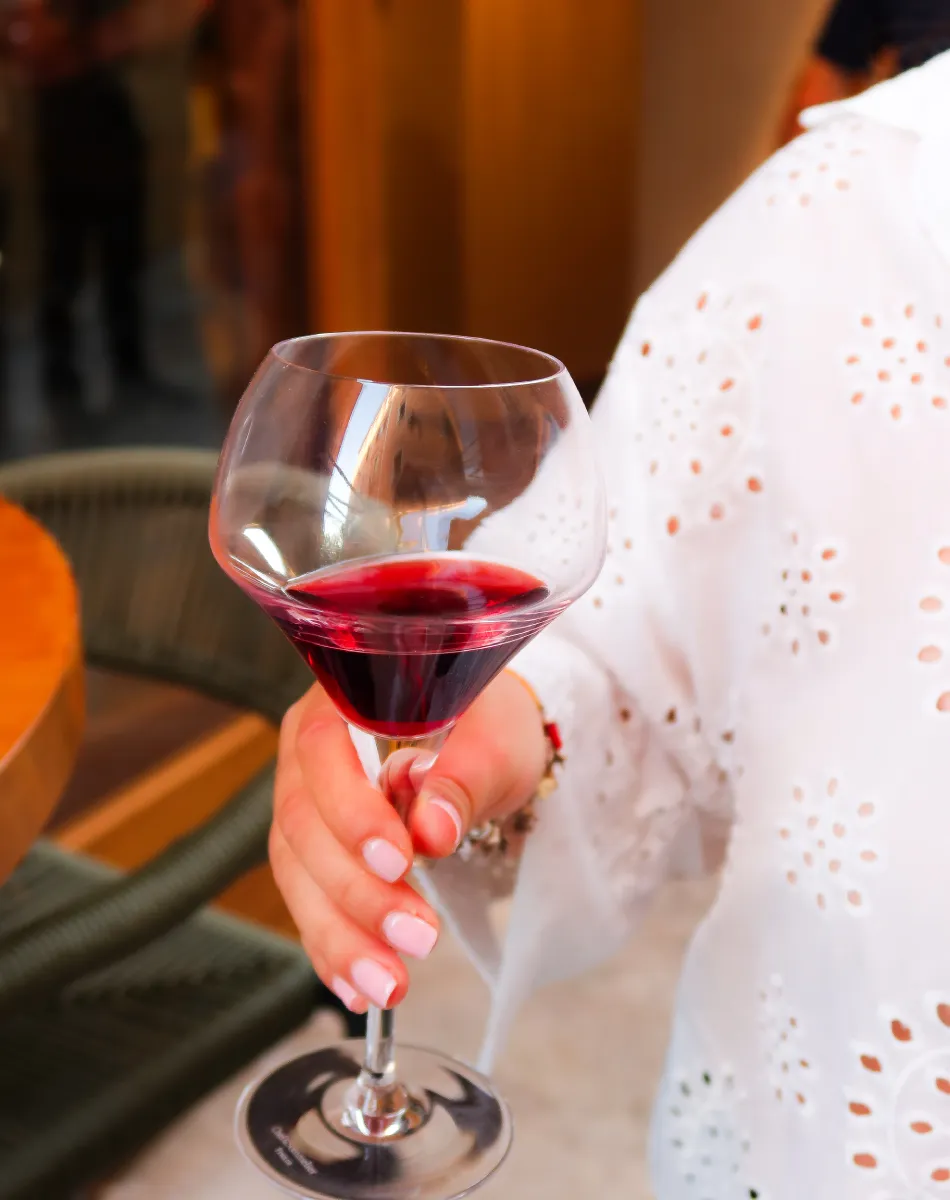 Dégustation de vin rouge | LA TABLE DES CLOS Personne tenant un verre de vin rouge